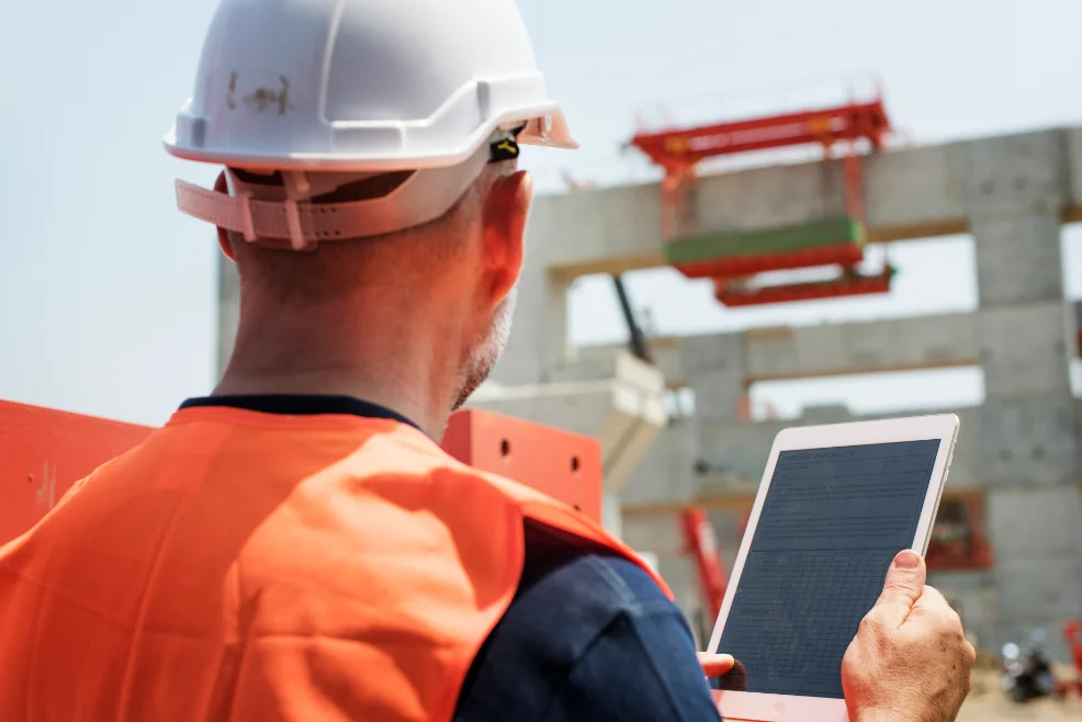 Trabajador con casco y tablet supervisando una obra en construcción